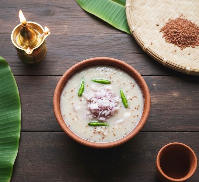 Traditional Kerala Pazhamkanji with overcooked red matta rice mixed in curd and topped with shallot pieces and whole green Kanthari chillies, served in a mud bowl.