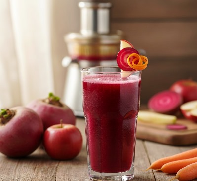 Homemade healthy ruby red juice served elegantly in a wine glass, prepared with natural ingredients like fresh beets and carrots.